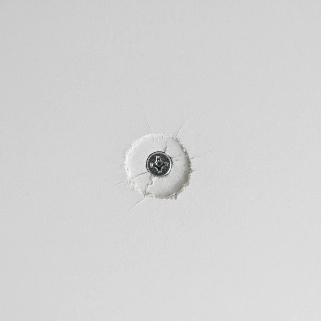 A screw head driven to a dimple in a sheet of ceiling board
