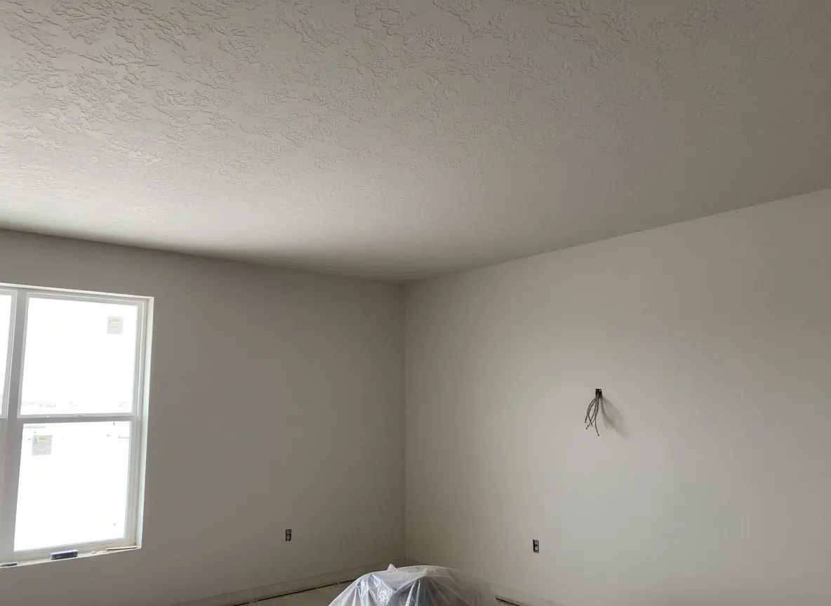 A finished ceiling and upper wall carrying an even knockdown pattern